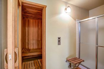 A sauna room with a shower and a wooden bench